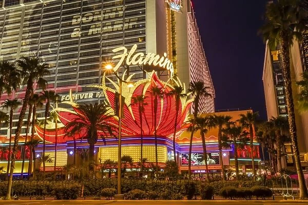 Neon lights, Las Vegas Strip at dusk with Flamingo Facade and palm trees, Las Vegas, Nevada, United States of America, North America
