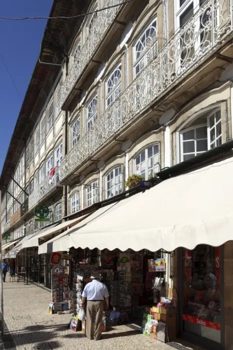 Framed Print : A newsagents stand under a building with a wrought iron balcony on the Largo do Toural Framed Print : A newsagents stand under a building with a wrought iron balcony on the Largo do Toural