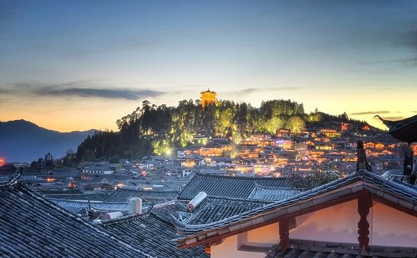 Night falls over Lijiang and Shizishan (Lion Hill with WanGu Tower) while the city lights slowly come to life, Lijiang, Yunnan, China, Asia