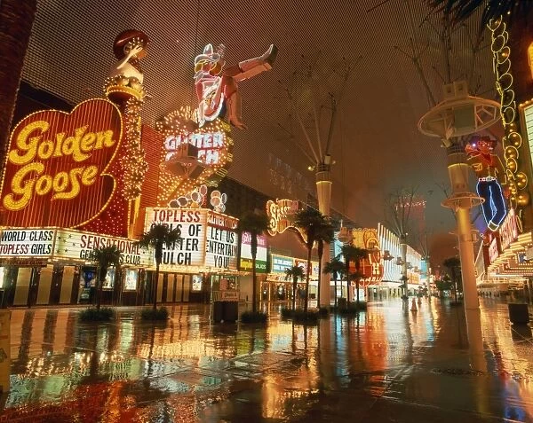 Night reflections on wet street of neon signs along Fremont Street in Las Vegas