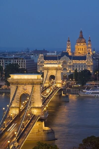 Night view of the Chain Bridge (Szechenyi Lanchid), illuminated, over the River Danube with the Gresham Hotel, St. Stephens basilica, and the Pest side behind, Budapest