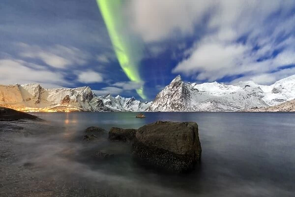 Northern Lights (aurora borealis) illuminate Hamnoy village and snowy peaks, Lofoten Islands