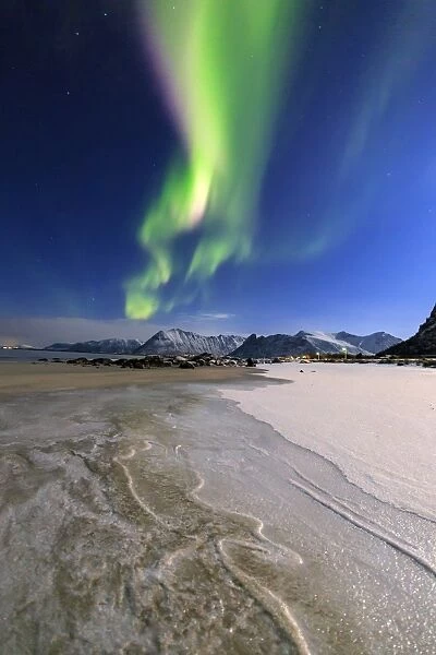 The Northern Lights (aurora borealis) light up the sky and the beach of the cold sea of Gymsoyand