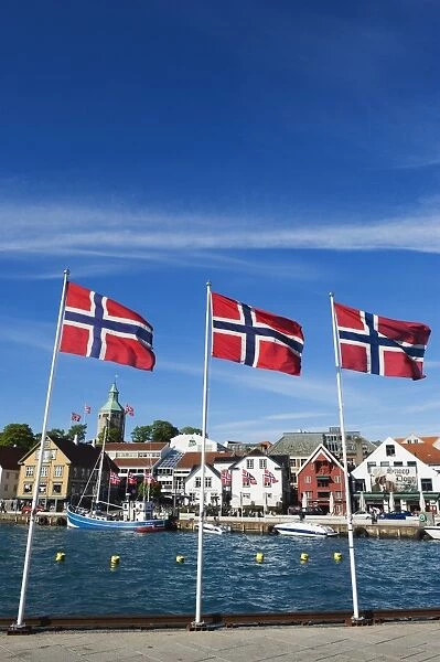 Norwegian flags and historic harbour warehouses, Stavanger, Norway, Scandinavia, Europe