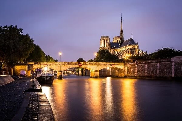 Notre Dame Cathedral and lights reflecting in the River Seine on a wet evening in Paris