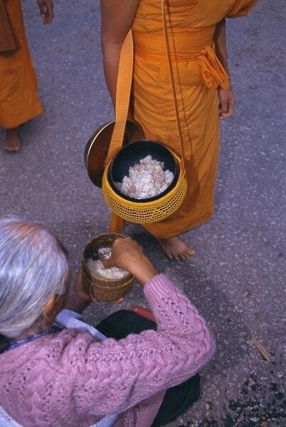 Novice monk receiving alms in the early morning