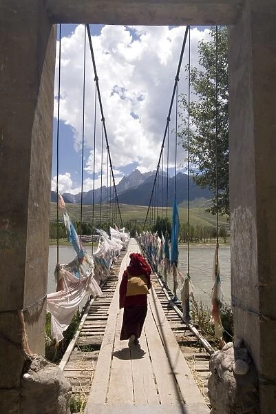 Nun walking across footbridge over Yalong river, Ganzi (Garze), Sichuan, China, Asia