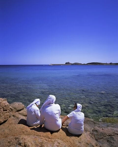 Three nuns sitting on rocks