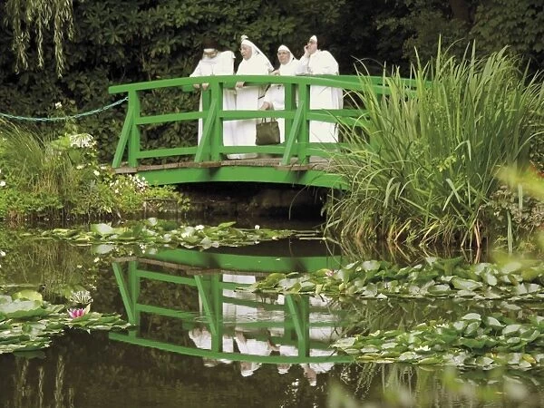 Four nuns standing on the Japanese bridge in the garden of the Impressionist painter Claude Monet