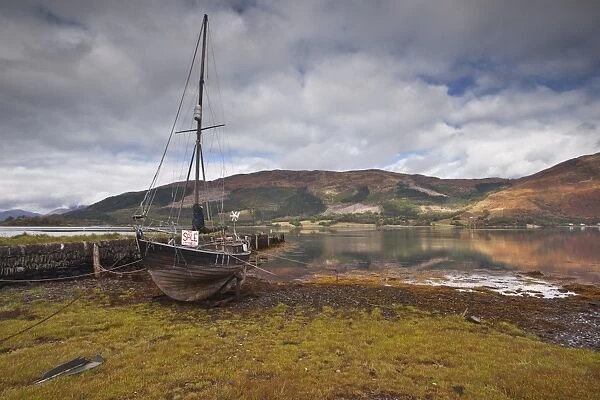 An old boat sits on the shore of Loch Leven in Glencoe, Highlands, Scotland, United Kingdom, Europe