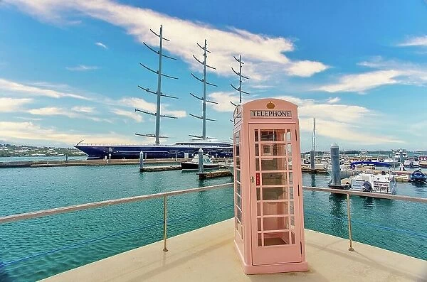 An old British telephone kiosk, with a three masted sailing ship moored behind, Hamilton, Bermuda, North Atlantic, North America