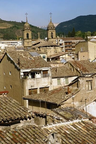Old buildings with tiled roofs and a church behind