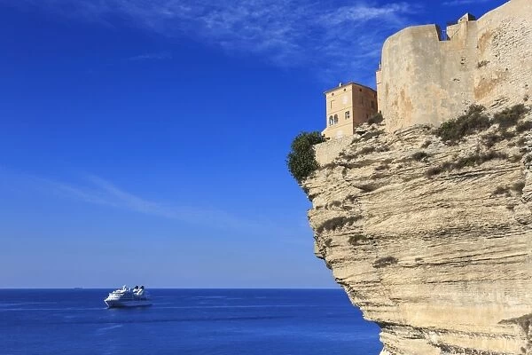 Old citadel atop cliffs with cruise ship anchored off shore, Bonifacio, Corsica, France