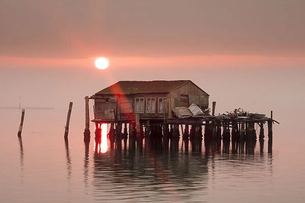 Old fishermens shack at sunset in Venetian lagoon off the coast of Pellestrina, Venice
