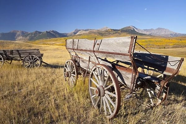 Old horse-drawn wagons with the Rocky Mountains in the background, near Waterton