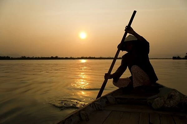 Old lady rowing in Hoi An harbour silhouetted at sunset, Vietnam, Indochina, Southeast Asia, Asia