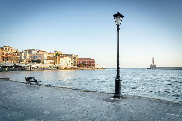 Old lantern in the Venetian harbour of Chania with lighthouse in background, Crete
