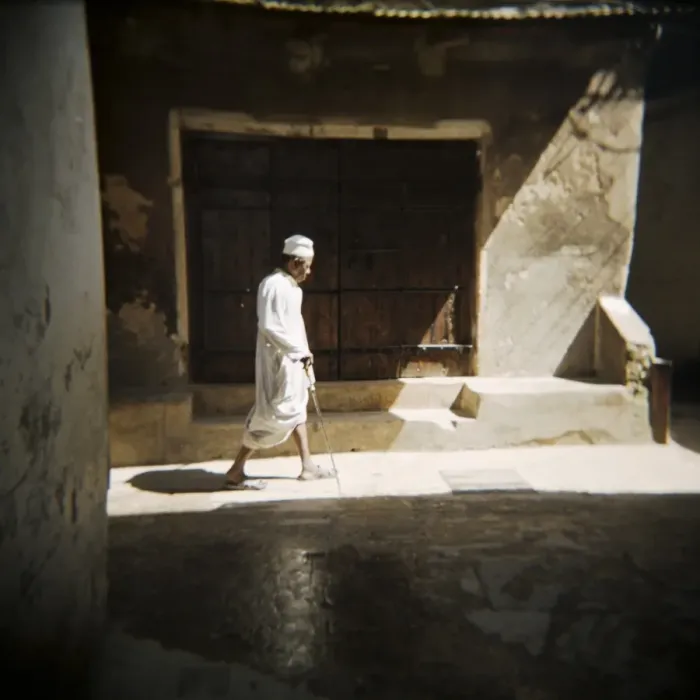 Framed Print : Old man walking down shady street in traditional white robes, Stone Town Framed Print : Old man walking down shady street in traditional white robes, Stone Town