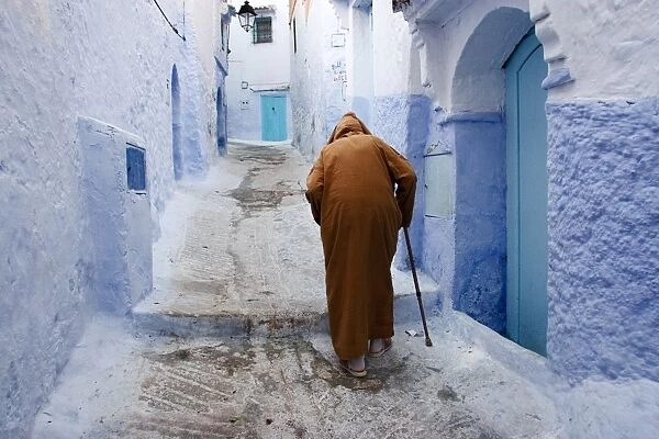 Old man walking in a typical street in Chefchaouen, Rif mountains region