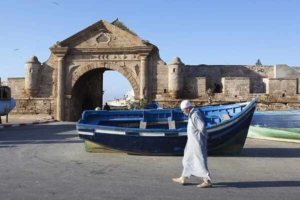 Old Muslim man walking below the old city gate and ramparts, Essaouira, Atlantic coast, Morocco, North Africa, Africa