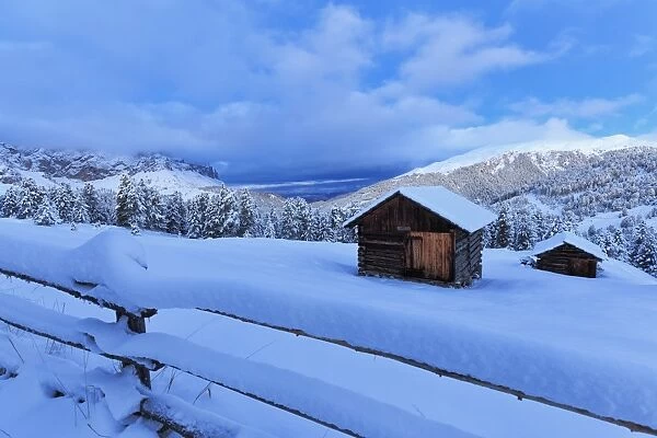 Old snow-covered huts during twilight, Erbe Pass, Funes Valley, Sudtirol (South Tyrol)