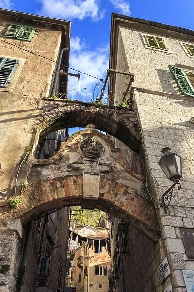 Old Town (Stari Grad), arch way with relief and hanging washing in an alley, Kotor