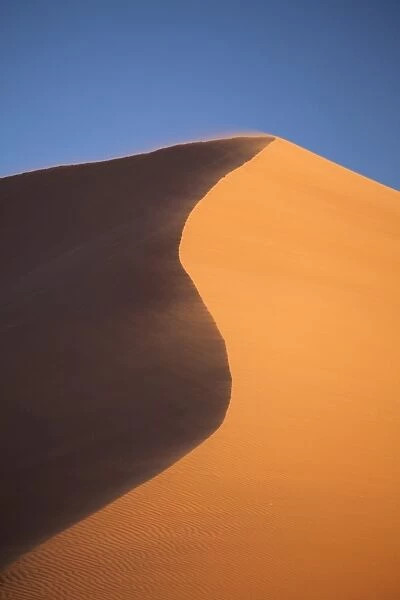 The orange sand and snaking ridge of Elim Dune against blue sky, Namib Desert near Sesriem, Namib Naukluft Park, Namibia, Africa