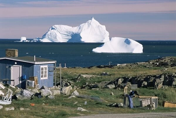 Painted wooden fishermans house in front of icebergs in Disko Bay