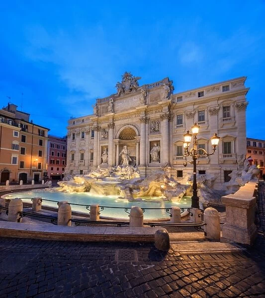 Panorama of Trevi Fountain illuminated by street lamps and the lights at dusk, Rome