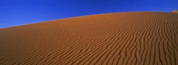 Panoramic view of orange sand dune and blue sky