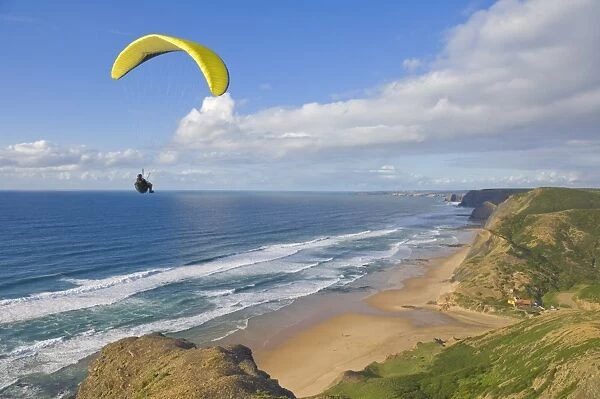 Paraglider with yellow wing above the south west coast of Portugal, Costa Vincentina
