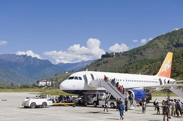 Passenger plane at Paro International Airport, Paro Rinpung Dzong in the distance