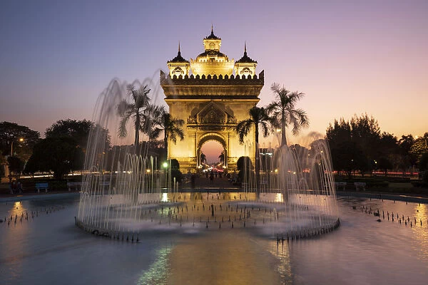 Patuxai Victory Monument (Vientiane Arc de Triomphe) and fountain floodlit at dusk