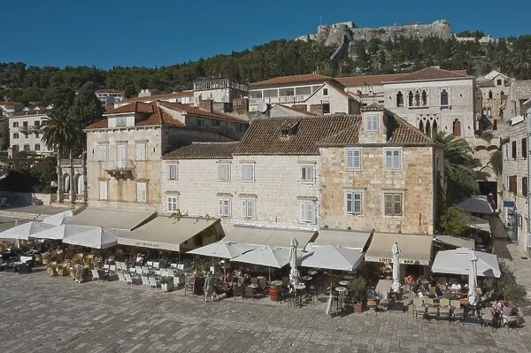 Pavement cafes in the main square overlooked by the ancient fortress, in the medieval city of Hvar, island of Hvar, Dalmatia, Croatia, Europe