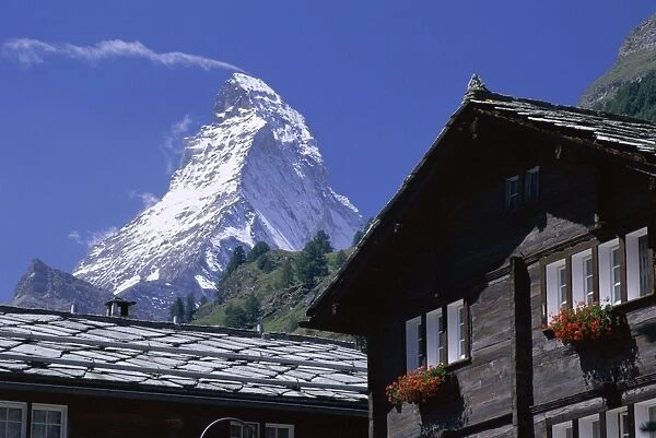 The peak of the Matterhorn mountain towering above chalet rooftops
