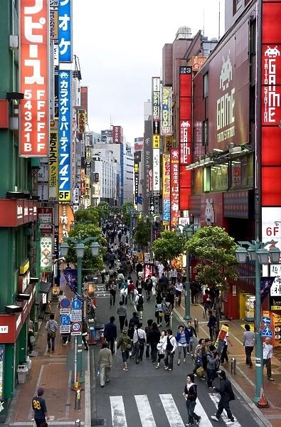 A pedestrian street lined with shops and signboards attracts a crowd in Shinjuku