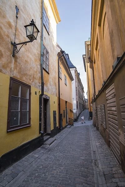 A pedestrian walks the streets of Stockholms colorful and historic Gamla Stan district