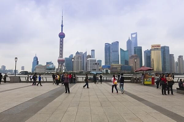 Pedestrians and tourists on the Bund, the futuristic skyline of Pudong across the Huangpu River beyond, Shanghai, China, Asia