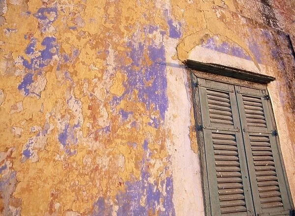 Peeling blue and ochre wall and shutters