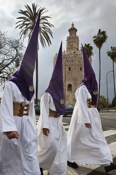Penitents during Semana Santa (Holy Week) beneath Torre del Oro, Seville, Andalucia, Spain, Europe