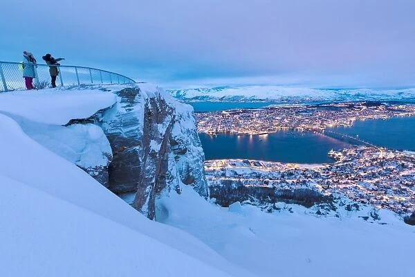 People admire the city of Tromso at dusk from the mountain top reached by the Fjellheisen cable car