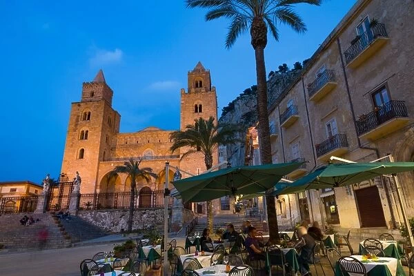 People dining in Piazza Duomo in front of the Norman Cathedral of Cefalu illuminated at night
