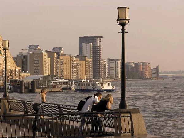 People looking at River Thames, with modern riverside flats beyond, the Canary riverside walk