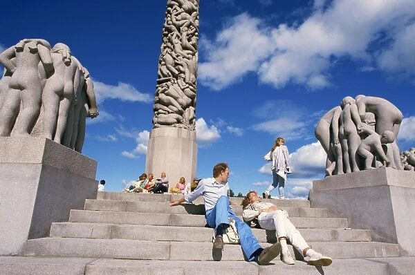 People relaxing on steps before sculptures on the central