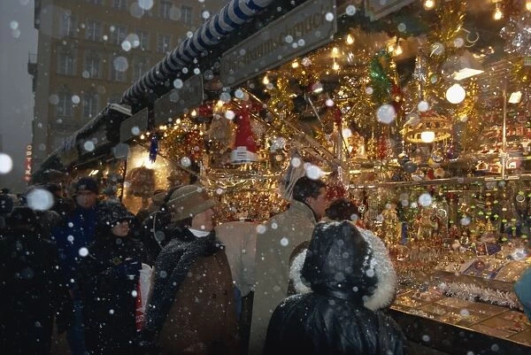 People shopping as snow falls at a Christmas market stall