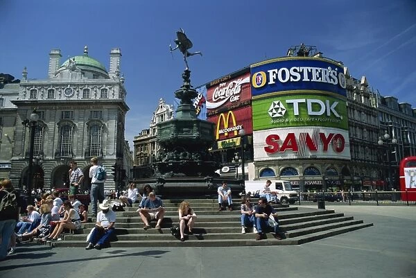 People sitting on steps below the Statue of Eros, Greek God of Love, erected in 1892 in memory of the Earl of Shaftesbury, Piccadilly Circus, London, England, United
