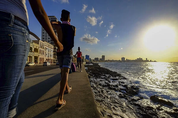 People walk along the Malecon as the sun sets, Havana, Cuba, West Indies, Central America