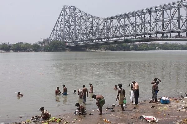 People washing in the River, Howrah Bridge in background, Kolkata, West Bengal