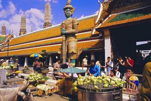 People worshipping and offering flowers in the Wat Phra Kaew complex
