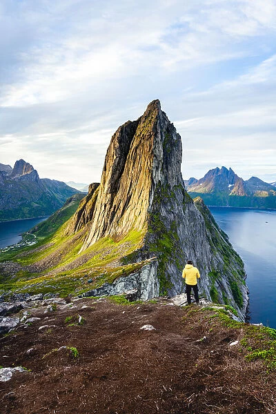 Person standing in front of tall Segla Mountain and fjords at dawn, Senja island